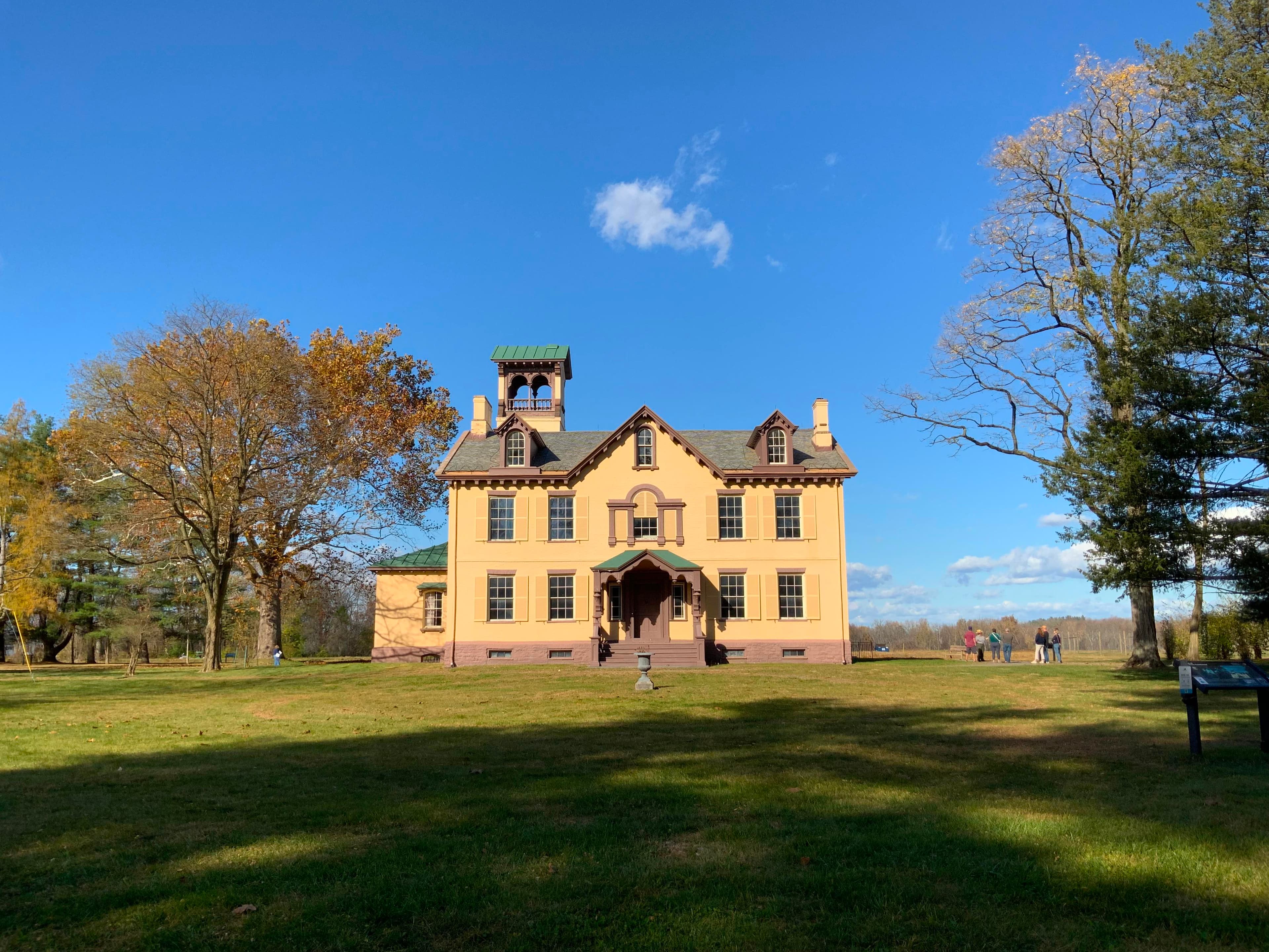 Lindenwald, a yellow, 3 story mansion, is surrounded by trees.